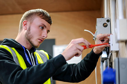 A young man in the electrical installation workshop is wiring a circuit