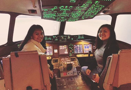 two students sitting in the pilot seats of an aircraft